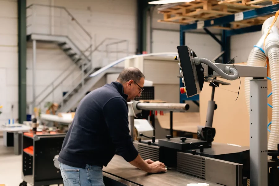 Medewerker zaagt een kunststofplaat op maat in het atelier